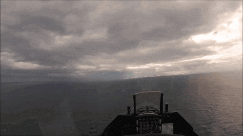 a fighter jet is flying over the ocean with a cloudy sky