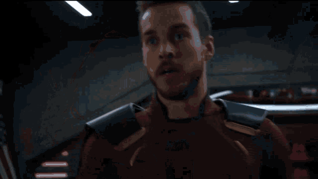 a man with a beard is wearing a red and black superhero suit .