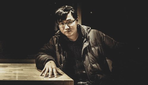a man sitting at a table with his hand resting on the table
