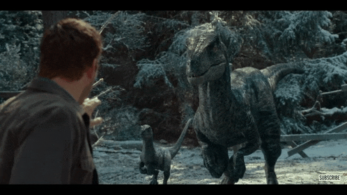 a man stands in front of a group of dinosaurs that are running in the snow