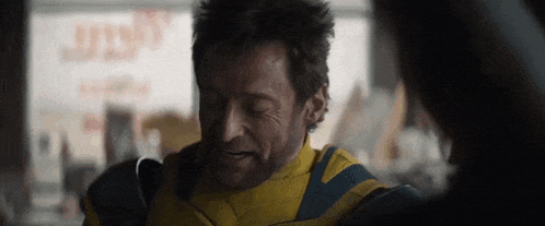 a man in a yellow and blue jacket is talking to a woman in a restaurant .