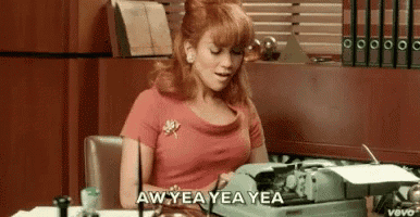 a woman is sitting at a desk typing on a typewriter and says aw yea yea yea .