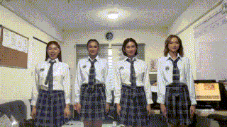 a group of young women in school uniforms and ties are standing in a room .