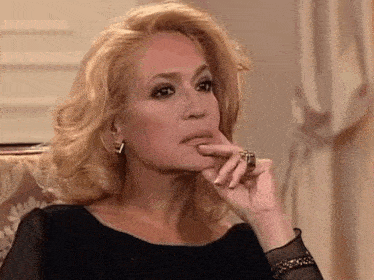 a woman is sitting on a couch with her hand on her chin .