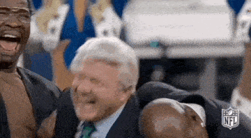 a man in a suit and tie is laughing while holding another man 's head .