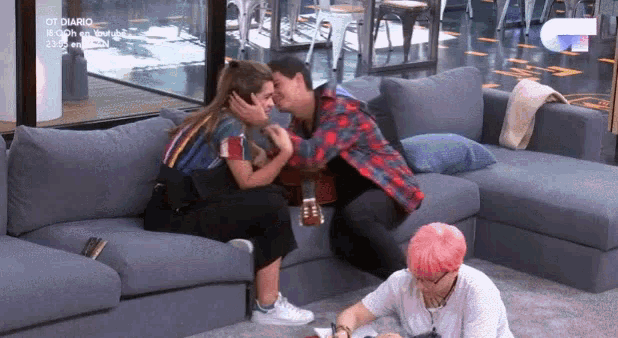 a man and a woman are kissing on a couch in a living room ..