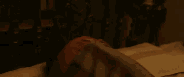 a man in a red shirt is laying on a bed looking at the camera