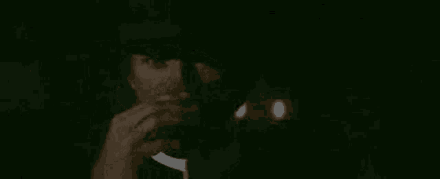 a man in a suit is smoking a cigarette in the dark .
