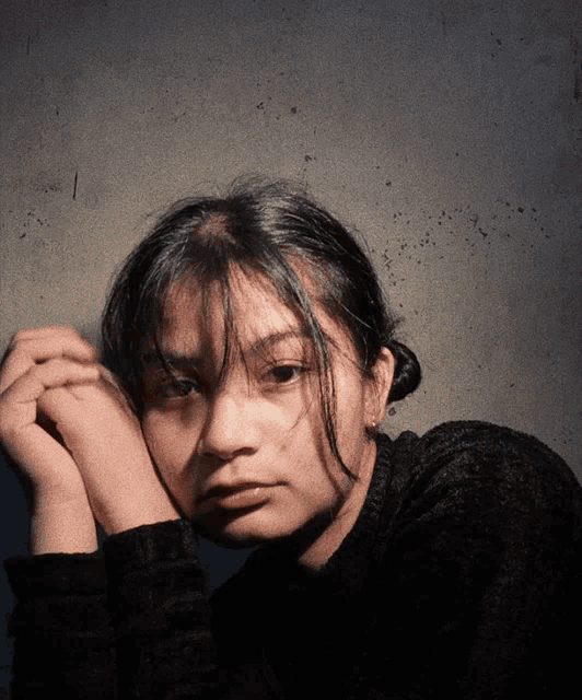 a young woman with her hands on her face looks at the camera