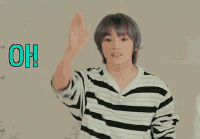 a young man in a striped shirt is raising his hand and says oh