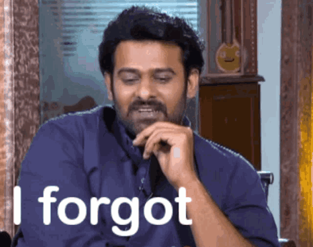 a man in a blue shirt says " i forgot " while sitting in a chair