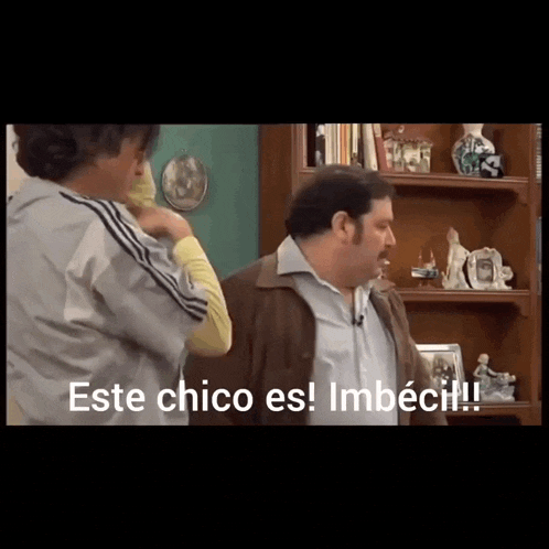 two men are standing in front of a bookshelf with the words este chico es imbecil on the bottom