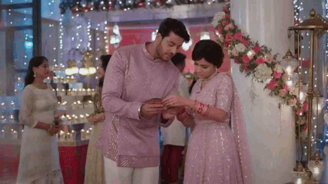 a man is putting a ring on a woman 's finger at a wedding