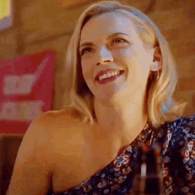 a woman is smiling while sitting at a table with a glass of wine .