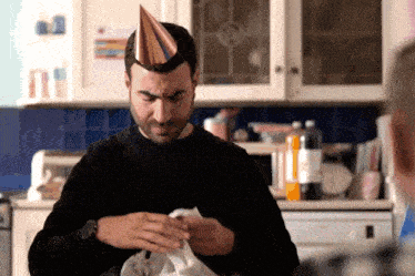 a man wearing a party hat holds a white shirt
