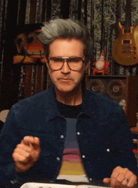 a man wearing glasses and a rainbow shirt is eating