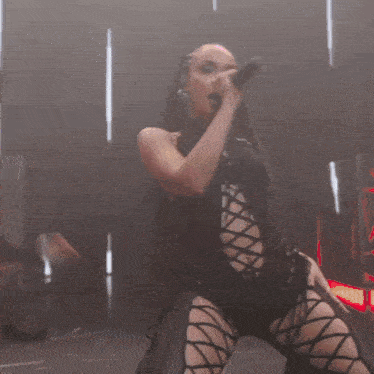 a woman is singing into a microphone while wearing a black outfit