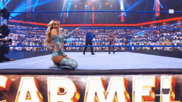 a woman is kneeling down in a wrestling ring with the name carmel written on the floor