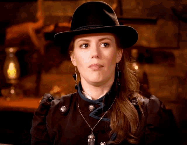 a woman wearing a black hat and a necklace with a skull on it