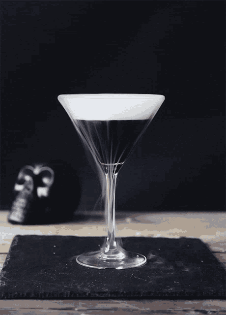 a martini glass with a skull in the background