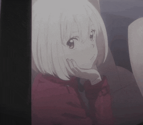 a girl with short white hair and a red coat is looking out a window .