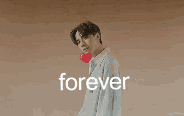a man is holding a red heart in his hand and the word forever is above him