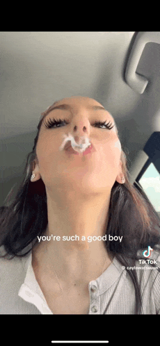 a woman in a car is blowing a cigarette out of her mouth with the caption you 're such a good boy