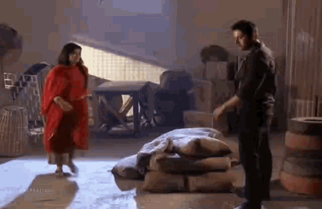 a man and a woman are standing next to each other in a room next to a pile of bags .