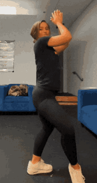 a woman is dancing in a room with a blue couch