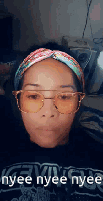 a woman wearing glasses and a headband with the words nyee nyee nyee written below her