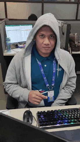 a man wearing a hoodie is sitting at a desk with a keyboard and mouse