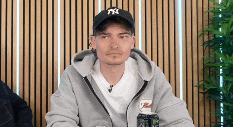 a man wearing a ny hat is holding a can of monster energy