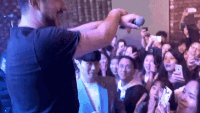 a man is standing in front of a crowd holding a microphone .