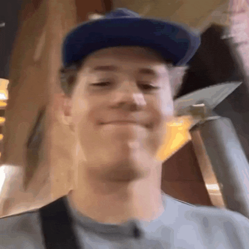 a man wearing a blue hat and a grey shirt is smiling .