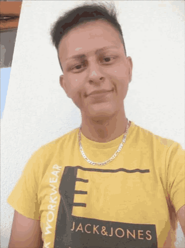 a man wearing a yellow jack & jones t-shirt takes a selfie