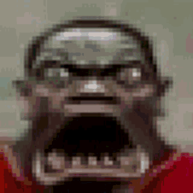 a pixelated image of a man with a beard wearing a helmet and a red shirt .