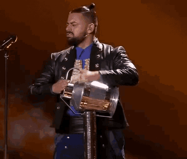a man with a beard and a leather jacket is holding a spotlight .
