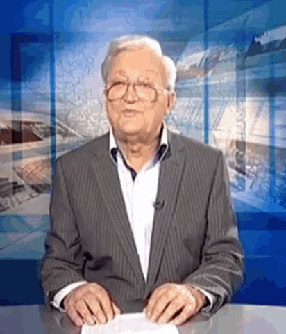 a man in a suit is sitting at a news desk