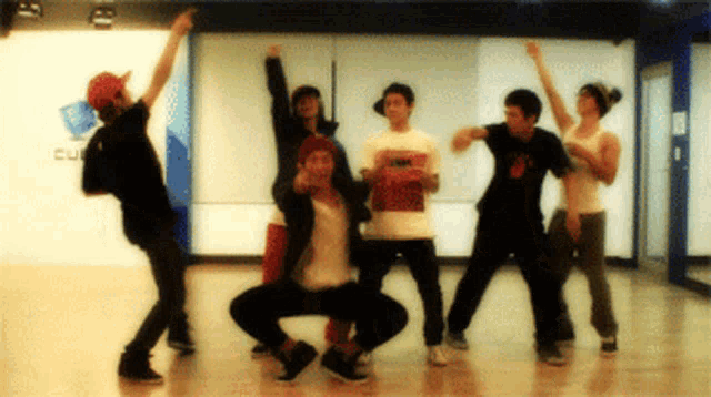 a group of young men are dancing in front of a wall with the word cube on it