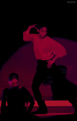 a man in a red shirt and black pants is dancing on a stage