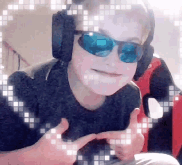 a young boy wearing headphones and sunglasses is making a heart shape with his hands