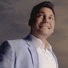 a man wearing a blue jacket and white shirt is smiling and looking up .