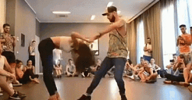 a man and a woman are dancing in a room while a crowd watches .