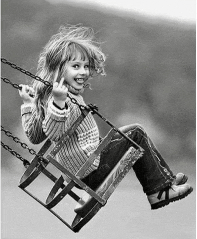 a little girl is sitting on a swing with her middle finger up