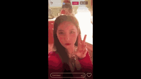 a woman is giving a peace sign while taking a selfie in front of a fire .