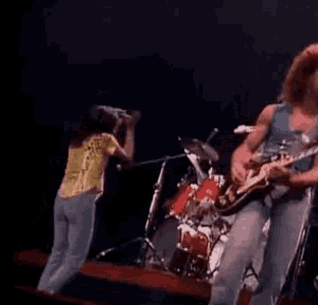 a man is playing a guitar on stage while a woman is dancing .