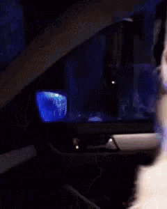 a person is sitting in a car with a blue light on the dashboard .
