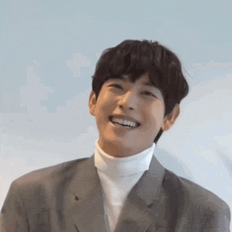 a close up of a man wearing a suit and a turtleneck smiling .