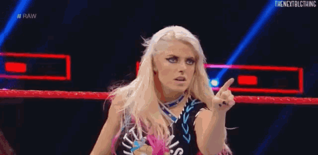 a woman is standing in a wrestling ring and pointing at the camera .