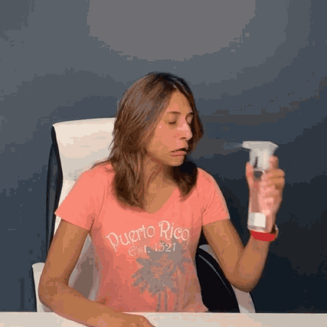 a woman wearing a pink puerto rico shirt is spraying something